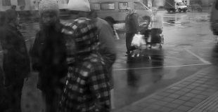 Изображены люди на вокзале, они в Тулой одежде, на улице мокро. Фотография размыта.